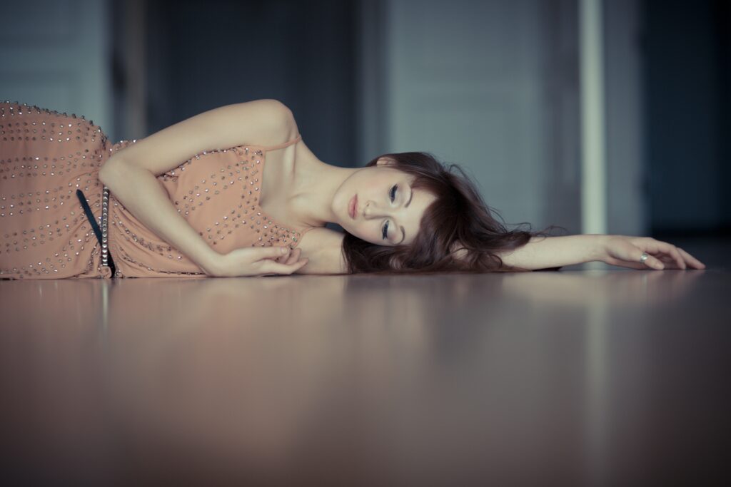 Woman laying on the floor, in a peach dress, looking sad and fed up.