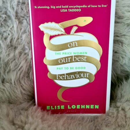 Elise Loehnen's hot pink book, On Our Best Behaviour against a sheepskin rug.