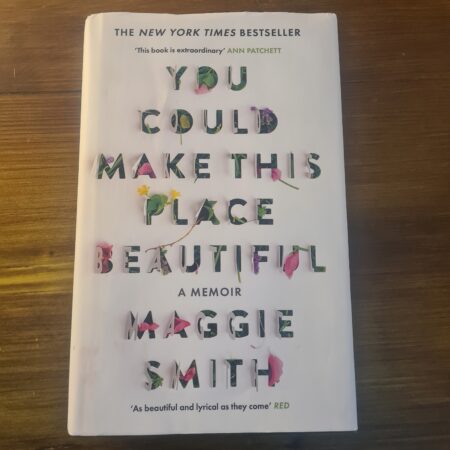 A picture of the front cover of the white hardback book You Could Make This Place Beautiful on a dark wooden table